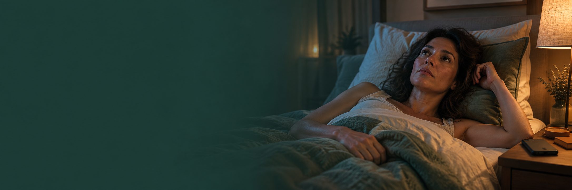 Pessoa acordada na cama à noite, com expressão pensativa e dificuldade para adormecer.